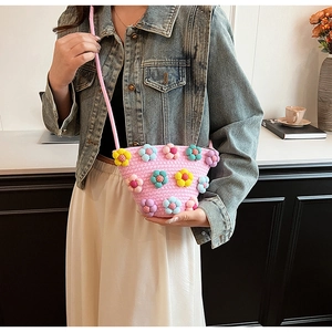 Detail of pink woven crossbody bag featuring colorful 3D crochet flowers and slim strap