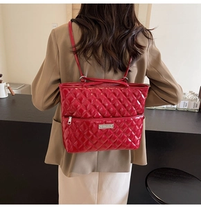 Detail of red quilted faux leather tote bag showing high-gloss finish and metal logo