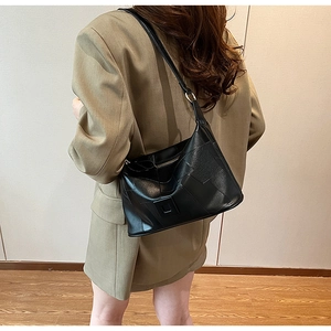 Minimalist black PU leather crossbody bag worn by a model in a stylish khaki blazer