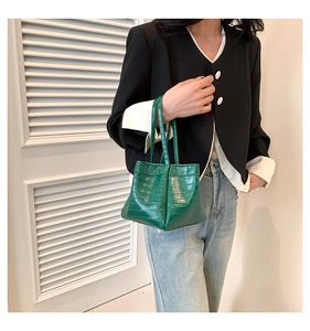 Detail of dark green crocodile embossed PU leather handbag with metal corner accents