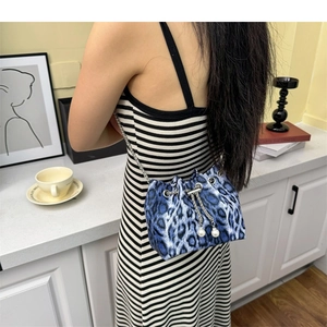 Detail of blue leopard print bucket bag with silver chain and white pearl charms