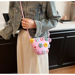 Detail of pink woven crossbody bag featuring colorful crochet flower decorations
