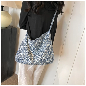 Detail shot of a blue and white floral canvas tote bag showing soft fabric drape and texture