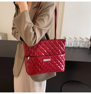 Close-up of wine red quilted PU leather tote bag with silver logo and polished texture
