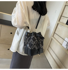 Detail showing frayed tassel denim bucket bag with gold hardware hooks and leather strap