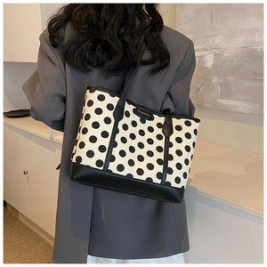 Polka dot canvas tote bag with black leather trim shown on a model in a modern room
