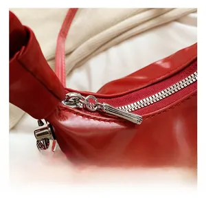 Close-up of shiny red PU leather bag featuring premium silver hardware and metal zippers