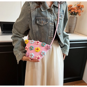 Detailed close-up of a pink woven crossbody bag with colorful 3D floral accents for women
