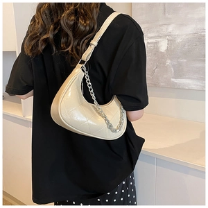 Modèle portant un sac en cuir PU matelassé beige en forme de croissant avec chaîne argentée