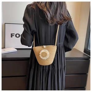 Straw woven bucket bag with sunflower detail and pearl button on black dress model
