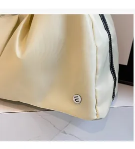 Dettaglio del tessuto in nylon a pieghe crema con logo circolare in metallo argentato