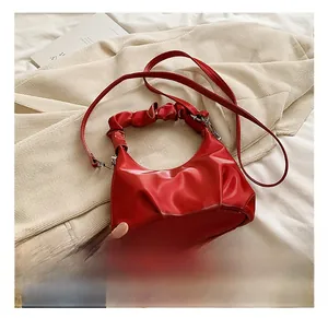 Detail showing red ruched crescent PU leather handbag with Muduo logo and slim strap