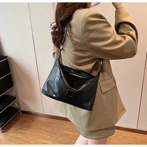 Minimalist black PU leather hobo shoulder bag with patchwork design on khaki suit model
