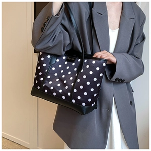 Close-up of stylish black and white polka dot tote bag with premium leather straps