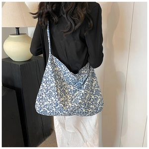 Detail of blue and white floral canvas tote bag shown from a back shoulder view