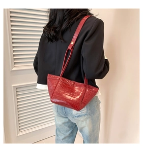 Fashionable dark red crocodile pattern PU tote bag carried by a model in a minimalist room