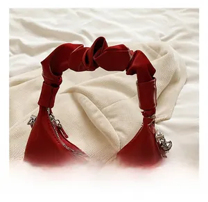 Detail of red PU leather bag showingRuched handle texture and silver metallic zipper closure