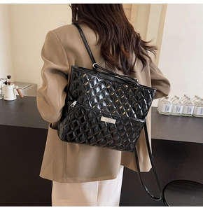 Model view of a large black quilted faux leather shoulder bag with glossy finish