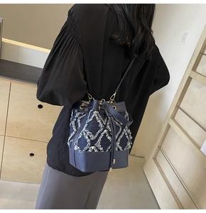 Detailed back view of a denim bucket bag with quilted frayed edges and chain strap