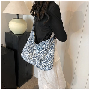Detail of blue floral canvas tote bag showing soft fabric texture and casual shoulder drape