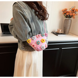 Detailed close-up of pink woven handbag with colorful 3D floral decorations and strap