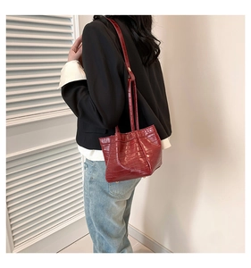 Close-up of dark reddish-brown PU leather handbag with crocodile pattern and metal studs