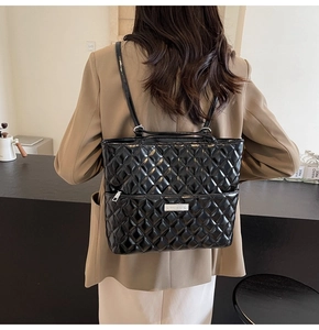 Quilted black PU leather backpack with sleek diamond pattern on a stylish khaki blazer