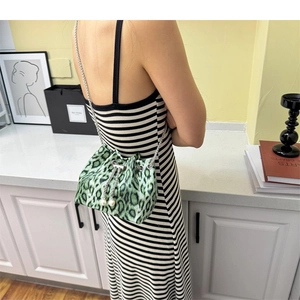 Close-up of green leopard print bucket bag with silver chain and pearl drawstrings