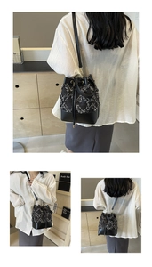 Detail of tweed bucket bag with black leather base and gold drawstring eyelets