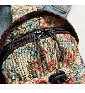 Detail showing smooth metal zippers on floral fabric crossbody bag with rope pulls