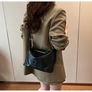 Close-up of black PU leather shoulder bag with patchwork texture and silver zipper detail