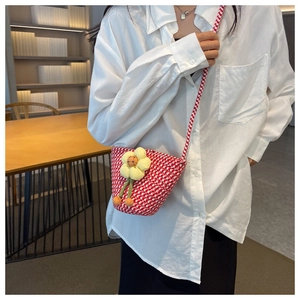 Detail of red and white checkered woven crossbody bag with a 3D yellow flower