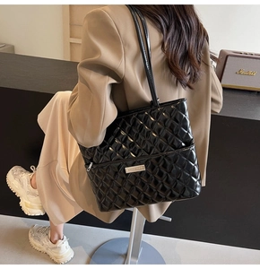 Model showing a black quilted PU leather tote bag with glossy finish and metal logo