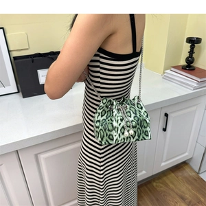 Detailed view of green leopard print bucket bag with metal chain and large pearl accents