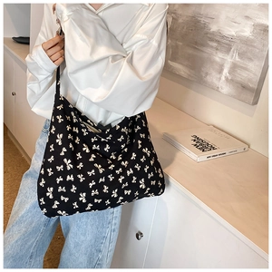 Chic black canvas crossbody bag with white bow print styled with casual denim and shirt