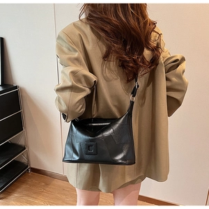 Detail of minimalist black PU leather crossbody bag with square buckle on a model