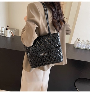 Detail of black quilted PU leather tote bag with glossy finish and brand logo tag