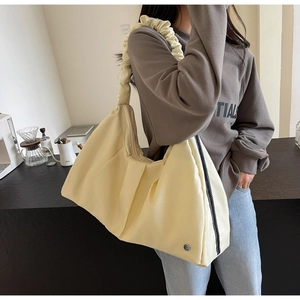 Dettaglio di una borsa tote giallo crema con tracolla arricciata dal design unico