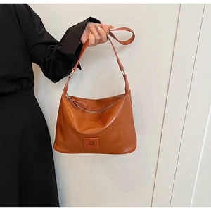 Close-up of orange PU leather shoulder bag with stitching detail and metal zipper