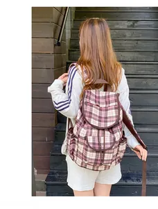 Detail view of plaid nylon backpack on outdoor model featuring multiple pockets and straps