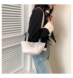 Detail shot of white crocodile embossed PU handbag with gold protective metal studs