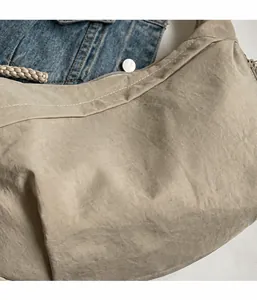 Detalle del bolso bandolera beige en nailon texturizado con correa de cuerda suave y ligera