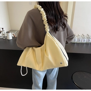 Dettaglio di una borsa a tracolla oversize in nylon giallo crema con spallina arricciata