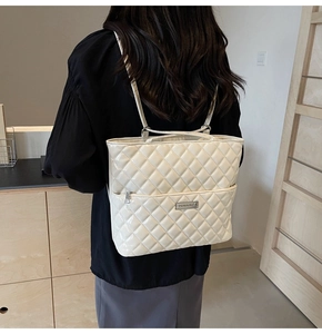 Rear view of cream quilted PU leather backpack handbag shown on person in a cozy interior