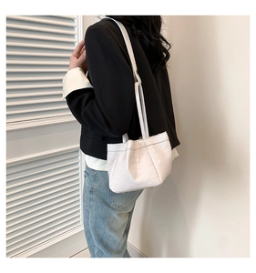Detail view of white crocodile pattern PU leather shoulder bag on a female model