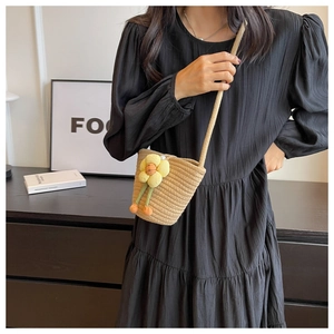 Close-up of beige woven bucket bag with yellow flowers and long shoulder strap