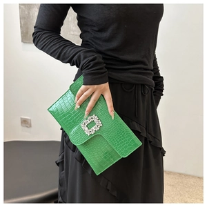 Detail of a bright green crocodile embossed clutch featuring a luxury square crystal buckle