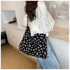 Detailed back view of model wearing a black canvas tote bag with white bow prints