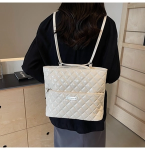Detail of cream patent leather backpack with quilted pattern and thin shoulder straps