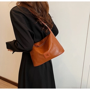 Detailed view of brown PU leather hobo bag with vertical stitching and smooth metal zipper